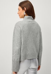 Maglione grigio a maglia con colletto alto, polsini e orlo a coste. Fit casual e ampio, texture morbida e design minimal.