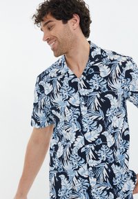 Korte mouw button-up shirt in marineblauw met lichtblauw tropisch bladdessin, voorzien van een kraag en twee knopen aan de voorkant.