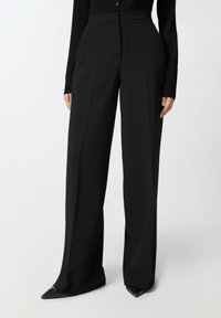 Crne krojene hlače s visokim strukom, naboranim prednjim dijelom i širokim nogavicama. Izrađene od glatkog materijala, s čistim završetkom i bez vidljivih hardverskih detalja.