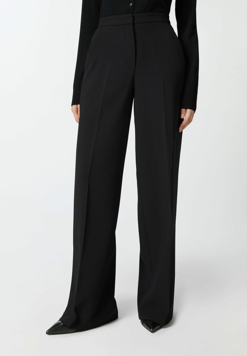 Crne krojene hlače s visokim strukom, naboranim prednjim dijelom i širokim nogavicama. Izrađene od glatkog materijala, s čistim završetkom i bez vidljivih hardverskih detalja.