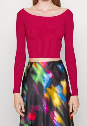 Tæt-siddende ribbet crop top i livlig fuchsia med off-the-shoulder design. Parret med en flydende, flerfarvet, abstrakt mønstret nederdel.