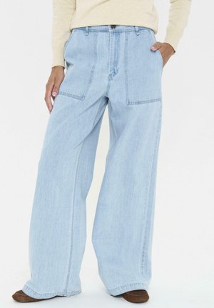 Helle blaue, weit geschnittene Jeans aus Denim mit einem rohen Saum und doppelten aufgesetzten Taschen auf der Vorderseite. Der Stoff hat eine weiche, strukturierte Oberfläche.