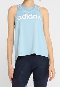 Helles blaues Adidas-Tanktop mit geripptem Halsausschnitt, weiten Armausschnitten und einem großen weißen Logo. Verfügt über Netzdetails für Atmungsaktivität.