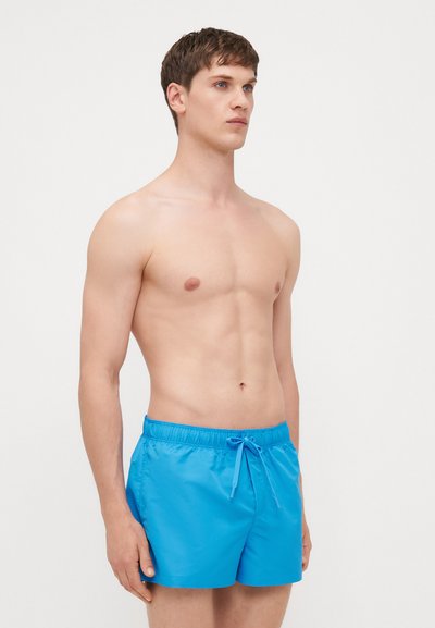 Shorts de bain bleus en tissu léger et lisse, dotés d'une taille élastique et d'un cordon de serrage. Présente un design simple et uni.