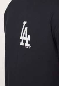 Fekete kapucnis pulóver, a hátsó részén fehér "LA" logóval és egy kis fehér MLB logó címkével. Puha, pamutszerű anyagból készült, sima tapintással.