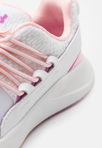 White athletic shoe with light pink accents, textured gray fabric, and elastic laces. Features a smooth sole and subtle branding detail.