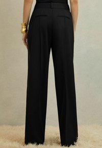 Melnas pielāgotas bikses ar plaša kāju dizainu, ar gludu tekstūru, divām aizmugures kabatām un spīdīgu apdari.