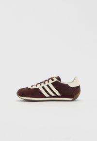 Burgundy sportcipő fehér csíkokkal, szövet felsőrész, kerek orr, fűzős kialakítás, gumitalp és texturált sarok részlet.