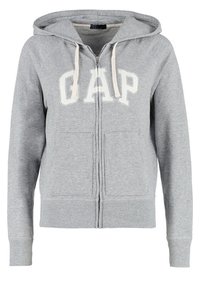 Sudadera con cremallera gris hecha de una mezcla de algodón, que presenta un logo frontal "GAP" en blanco, dos bolsillos laterales y una capucha con cordón.