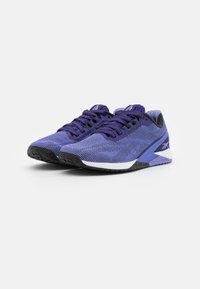 Une paire de chaussures de sport Reebok violettes et noires avec une tige en mesh et une semelle rembourrée sur fond blanc.