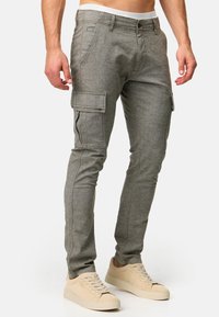 Pantalones cargo grises con un diseño ajustado, bolsillos frontales y bolsillos cargo laterales; hechos de una tela texturizada. Combinados con zapatillas beige.