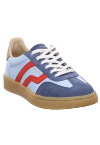 Zapatillas informales con un empeine de gamuza azul y blanca, franjas de acento rojas, cordones blancos, talón marrón y una suela de goma texturizada.