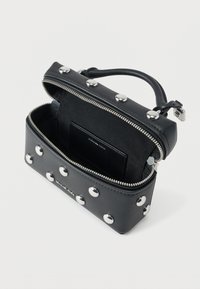 Zwarte leren handtas met zilverkleurige studs, bovenhandvat, rits open en binnenvak voor kaarten met merknaam op een witte achtergrond.