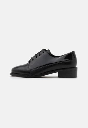 Chaussures en cuir noir avec une finition brillante, à lacets, bout arrondi et talon bas en bloc. Présente une texture lisse et des coutures discrètes.