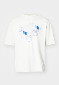 Bílý tričko s krátkým rukávem se modře orámovanými a vyplněnými písmeny "A C W" a geometrickými liniovými vzory přes hruď.