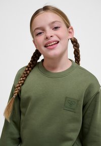 Felpa in cotone verde con colletto rotondo e un patch logo testurizzato sul petto, caratterizzata da maniche lunghe e una vestibilità rilassata.