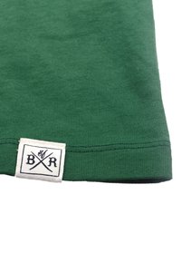 Vihreä viiruinen kangas suoran helman kera. Sisältää ommellun valkoisen tarran mustalla tekstillä ja ristiinviivatulla logolla. Liukas koostumus, rento muotoilu.