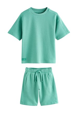 Zeleno mätová textúrovaná košeľa s krátkym rukávom a zodpovedajúce šortky so sťahovacou šnúrkou, ležérny štýl, uložené na plochu na bielom pozadí.