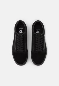 Sorte sneakers med en kombination af ruskind og tekstiloverside, flade snørebånd og en struktureret gummisål, med sorte detaljer og logo.
