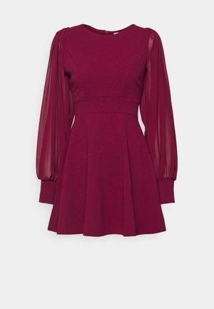Burgundy dress with a fitted bodice, flared skirt, and sheer long sleeves; features a round neckline and a concealed back zipper.