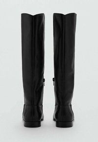 Czarne skórzane botki do kolan o zwężającym się kształcie, lekko wygiętych cholewkach i płaskim obcasie. Posiadają boczne zamki błyskawiczne, co ułatwia zakładanie.