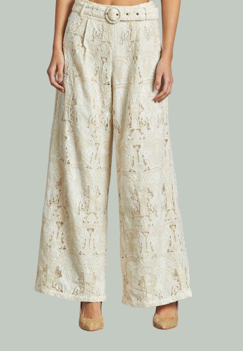 Pantaloni a gamba larga color crema con dettagli in pizzo intricati. Presentano una vita con cintura e tasche laterali, con una finitura texturizzata su tutta la superficie.