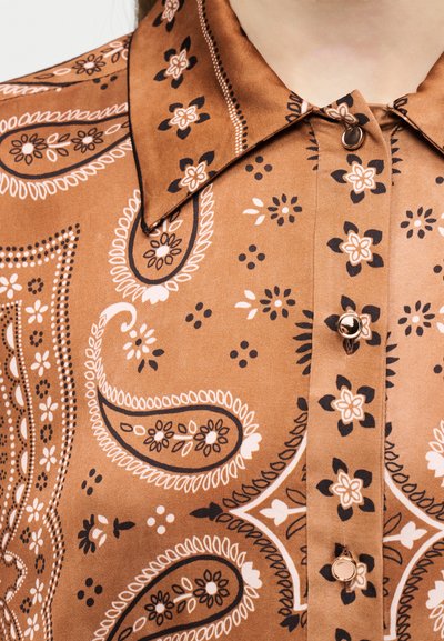Καφέ πουκάμισο με μοτίβο πεϊζλί, μαύρα και λευκά λουλουδένια σχέδια και μικρά στρογγυλά κουμπιά, με μυτερό γιακά.