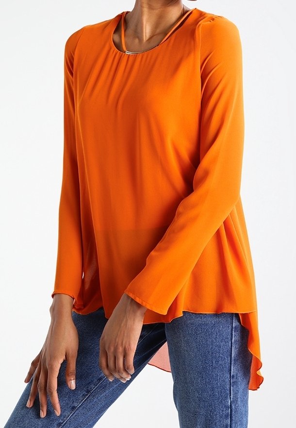 Blouse orange à manches longues, col rond et ourlet fluide. Confectionnée dans un tissu léger à texture lisse. Détail de design chic près du cou.