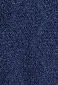 Marine textiel met een gestructureerd breipatroon en verhoogde diamanten vormen, wat een zachte en tastbare oppervlakte creëert.