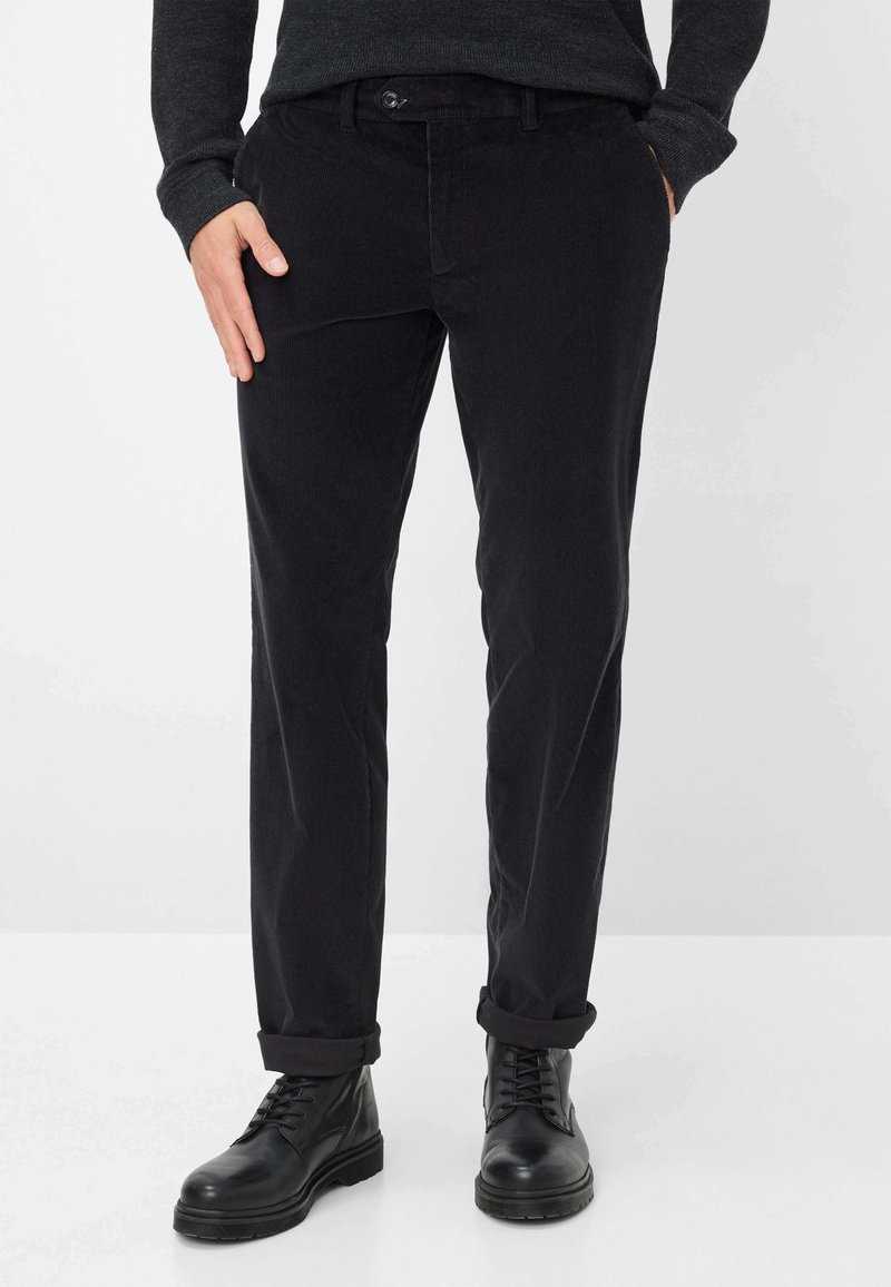 Zwarte corduroybroeken met een slim fit, voorzien van een knoopsluiting, zijzakken en opgerolde boorden, gecombineerd met zwarte leren laarzen.