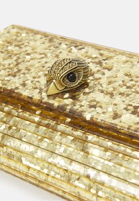 Clutch dorata con glitter, superficie testurizzata e una chiusura in metallo a forma di testa di uccello, caratterizzata da accenti scintillanti e dettagli degli occhi neri.