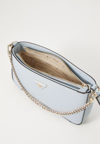 Sac à main synthétique bleu clair avec une finition texturée, des accessoires en or et une chaîne en bandoulière. Il dispose d'un intérieur zippé et de plusieurs compartiments.