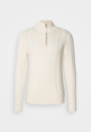 Suéter de punto en crema claro con cuello alto, cremallera parcial y diseño de punto trenzado con patrones texturizados en la parte delantera y las mangas.