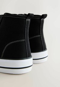 Mustad kõrge säärega lõuendist tennised valge kummist tallaga ja musta äärisega. Omavad kontrastset valget õmblust ja tagaküljel tõmbenutte.