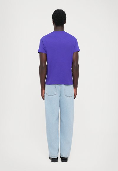 Μωβ βαμβακερό t-shirt με κοντά μανίκια, συνδυασμένο με ανοιχτό μπλε, φαρδιά τζιν παντελόνια. Απλή υφή, σχέδιο με κανονικό λαιμό.