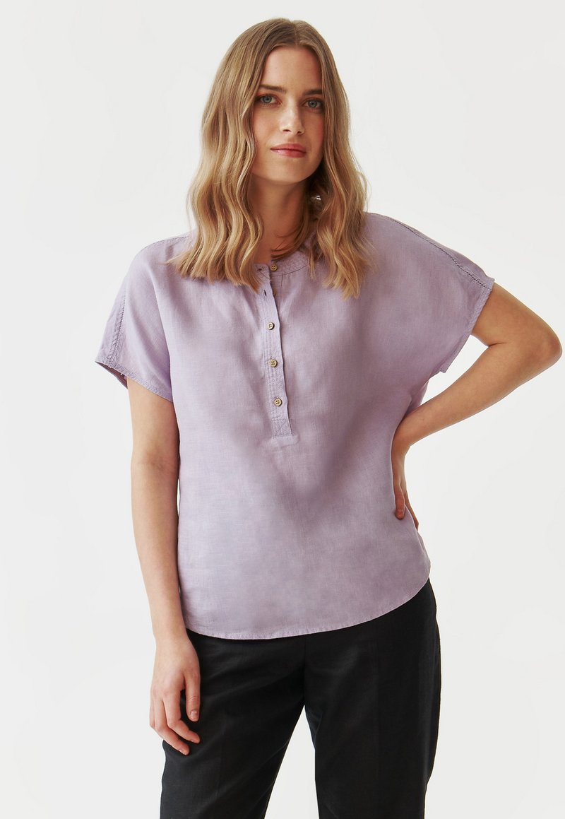 Licht lavendelkleurig shirt met korte mouwen, een knoopsluiting en een relaxte pasvorm. Gemaakt van een zachte, gestructureerde stof met een subtiele glans.