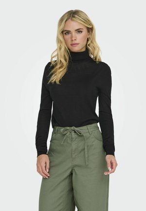 Svart långärmad polokrage topp som matchas med lösa, högmidjade olivgröna byxor med knytning i midjan och sidfickor.