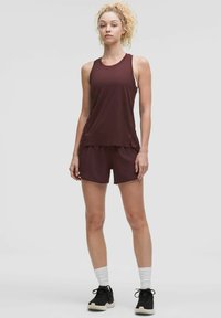 Mörkröd atletisk tanktop och shorts, med avslappnad passform, mjukt tyg och lagerdesign. Komplett med svarta sneakers och vita strumpor.