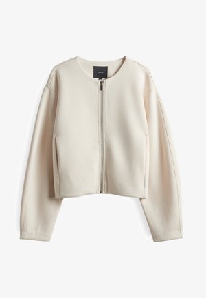 Veste cropped couleur crème en tissu lisse. Présente un col rond, une fermeture éclair à l'avant et des manches longues avec des poches latérales.