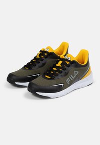 Mustat ja keltaiset urheilukengät, joissa on verkkomateriaali päällisosa, nauhat ja pehmustettu pohja, joissa on valkoisia yksityiskohtia ja iso logo sivussa.