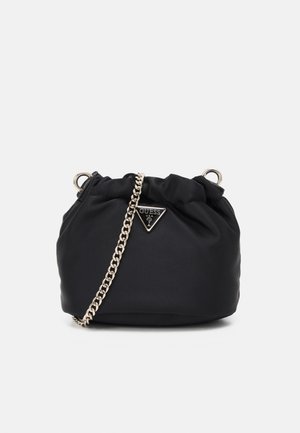 Sac à main en tissu noir souple avec une bandoulière en chaîne argentée et un logo Guess triangulaire sur le devant, avec un détail froncé en haut.