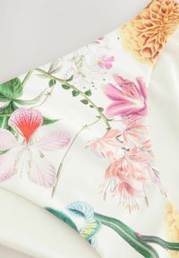 Bikiniunderdel med blommotiv som visar illustrationer av rosa, orange och gröna blommor mot en vit bakgrund, med en slät och mjuk textur.