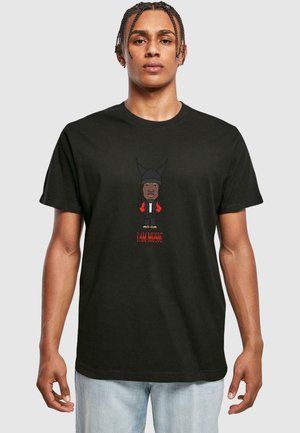 T-shirt en coton noir avec un personnage illustré portant une capuche, des accents rouges et le texte "JE SUIS DE LA MUSIQUE" en dessous. Manches courtes, coupe décontractée.