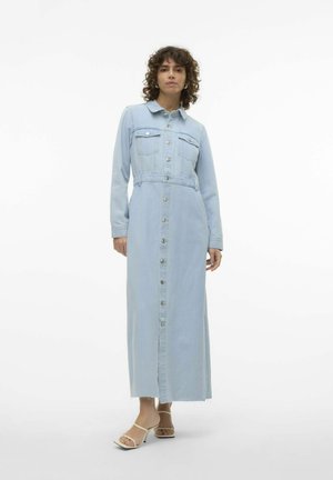 Robe chemise en denim bleu clair avec manches longues, fermeture à boutons sur le devant, deux poches poitrine et taille cintrée. Présente un ourlet brut et une texture subtile.