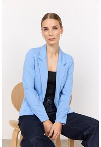 Sacou albastru deschis cu guler în formă de notch, design ajustat și mâneci lungi. Purtați peste un top negru, asortat cu blugi albastri închiși.