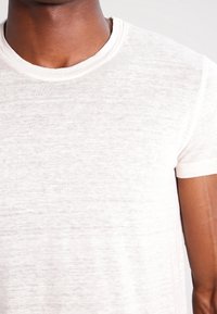 White short-sleeve t-shirt made of lightweight fabric, featuring a crew neckline and a slightly textured finish. No patterns or accents visible.