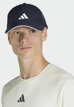 Námornícka šiltovka s bielymi akcentmi, s výrazným trojpruhovým logom na prednej strane a zakriveným šiltom. Hladká textúra látky.