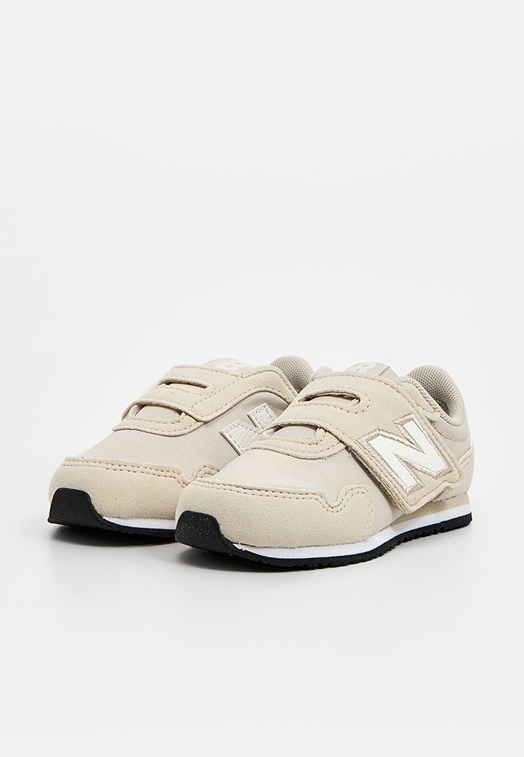 Sneakers beige con un upper in suede e mesh. Presentano cinturini regolabili in Velcro, una punta arrotondata e una suola in gomma nera texturizzata.