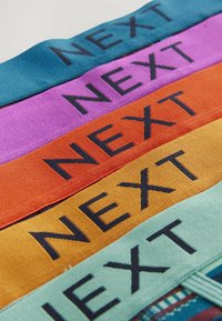 Benzile colorate din țesătură în nuanțe de teal, violet, portocaliu, galben și verde, cu text negru care scrie "NEXT" expus proeminent.