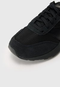 Baskets noires en tissu mélangé avec du mesh et du suédé, avec un embout arrondi et des lacets texturés. Semelle en caoutchouc pour une meilleure adhérence.